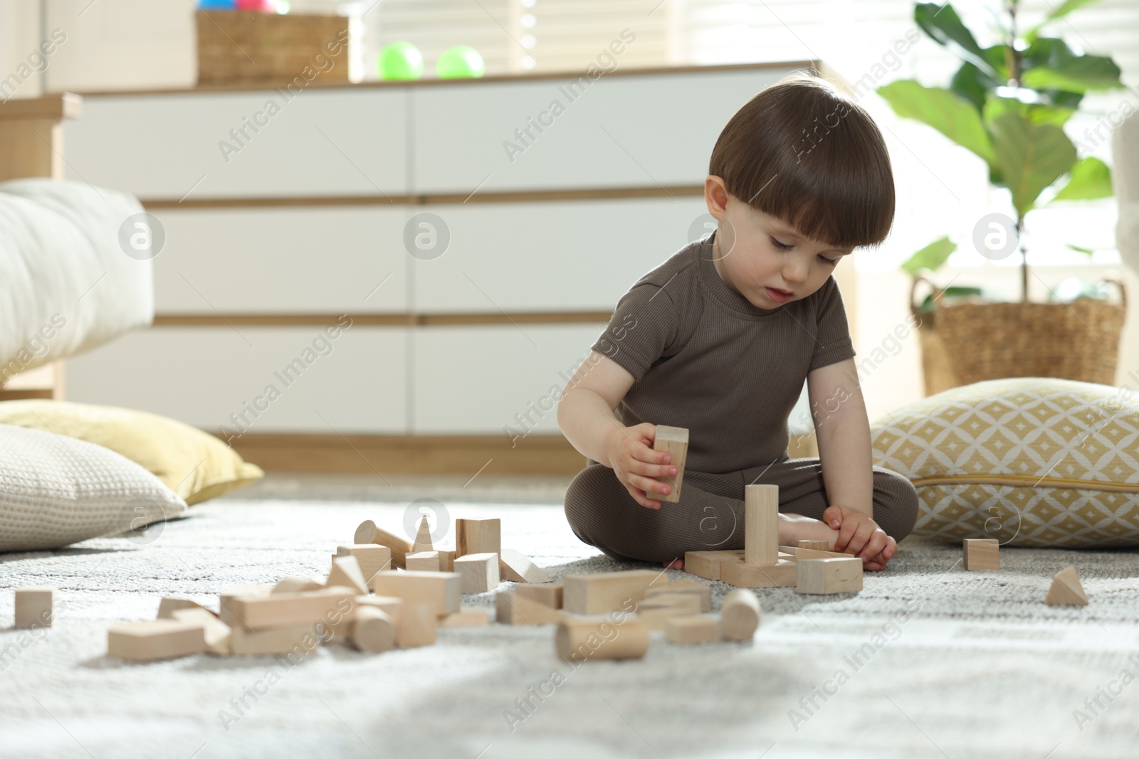 Photo of Cute little child playing with wooden building blocks at home. Space for text