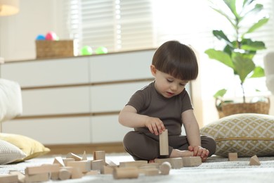 Photo of Cute little child playing with wooden building blocks at home. Space for text