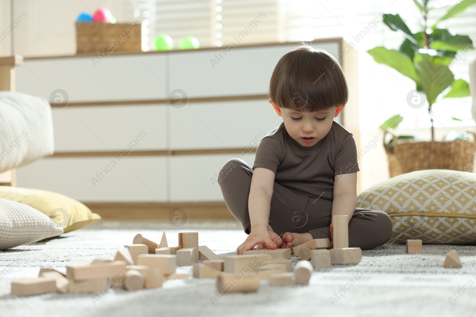 Photo of Cute little child playing with wooden building blocks at home. Space for text