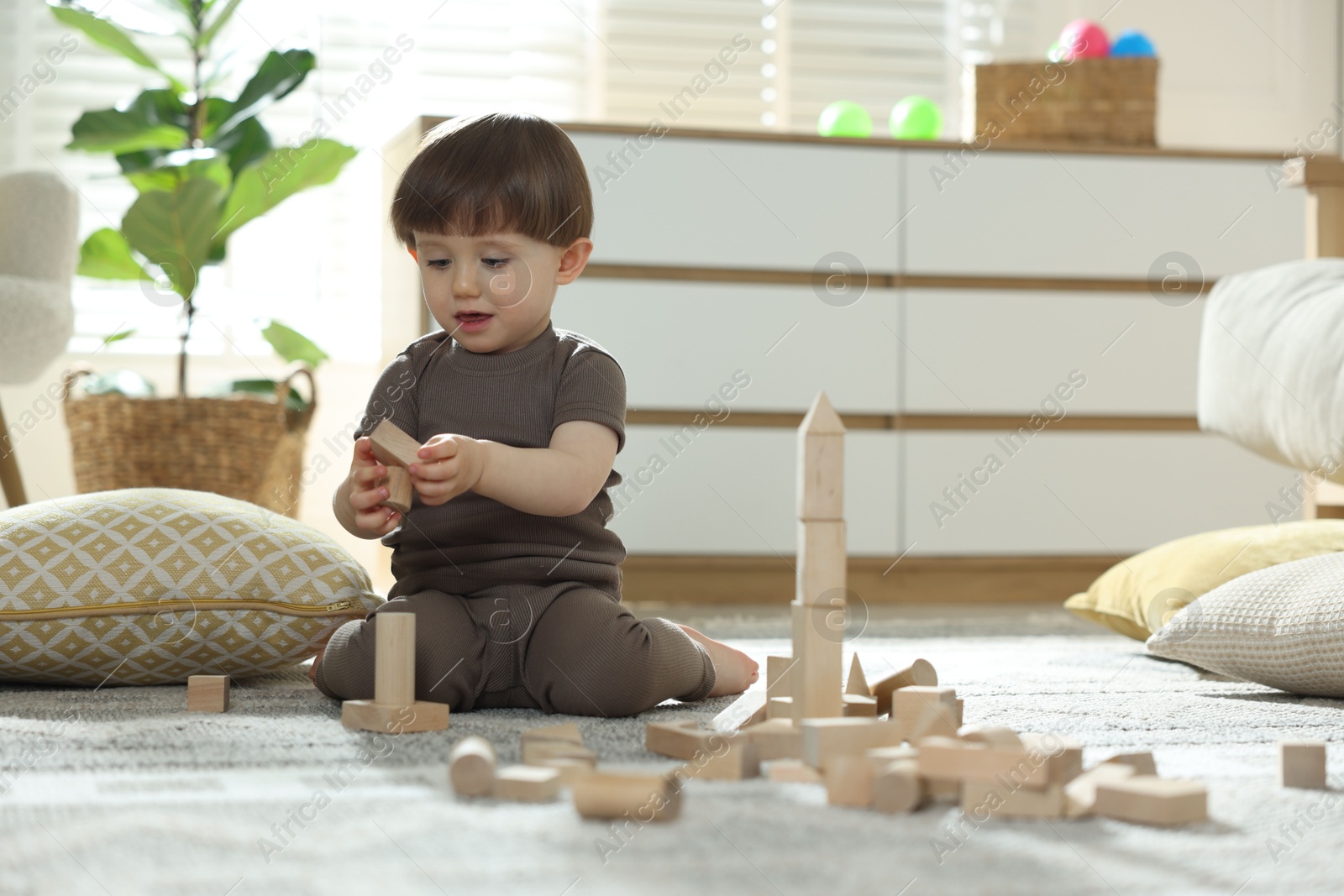 Photo of Cute little child playing with wooden building blocks at home. Space for text