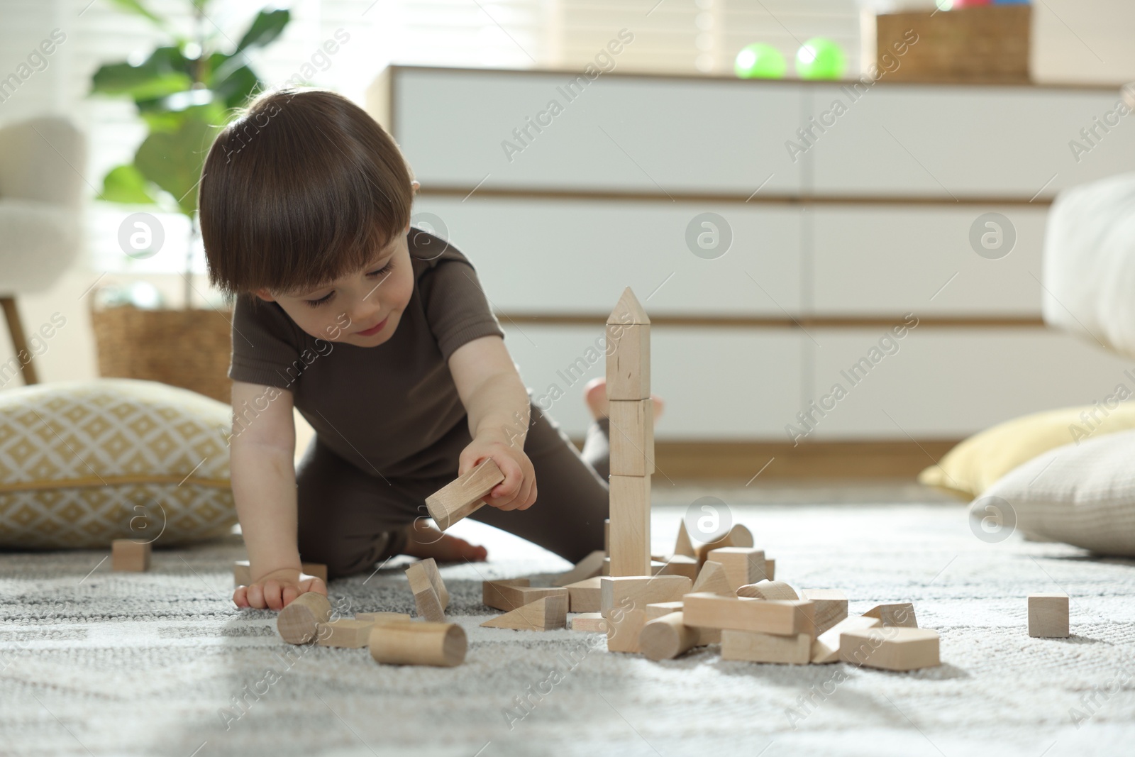 Photo of Cute little child playing with wooden building blocks at home. Space for text