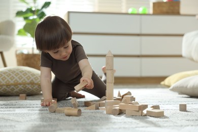 Photo of Cute little child playing with wooden building blocks at home. Space for text