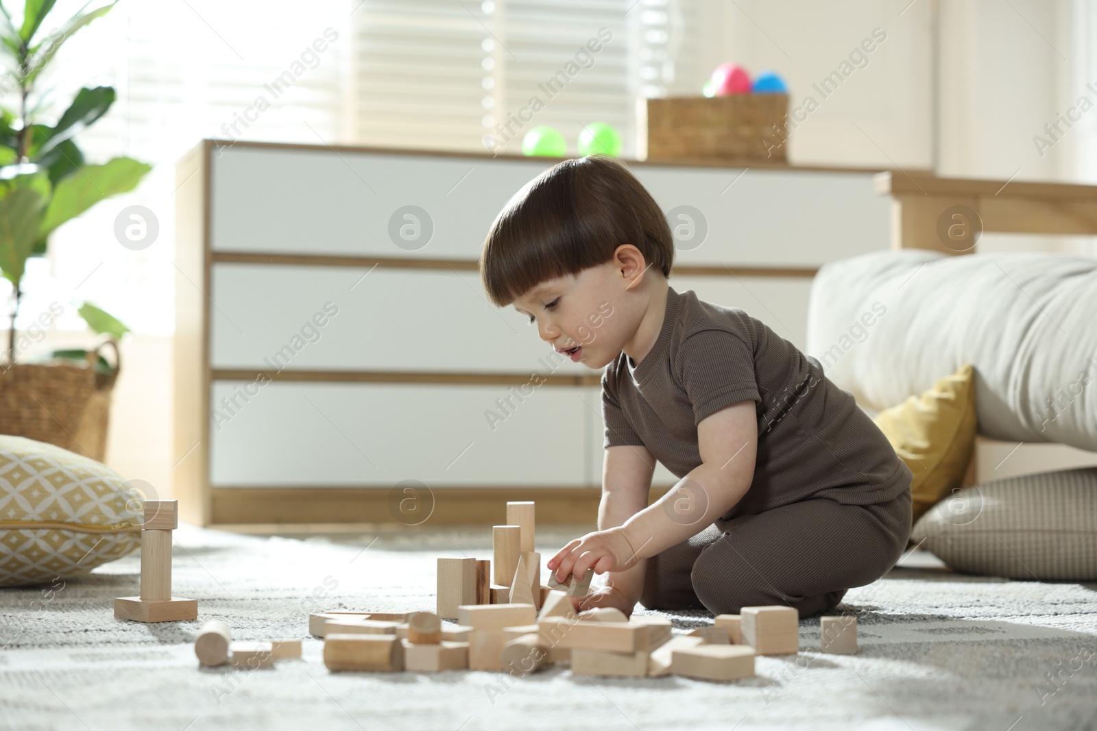 Photo of Cute little child playing with wooden building blocks at home. Space for text