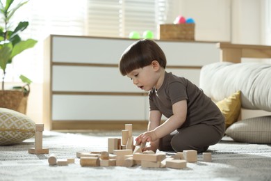 Photo of Cute little child playing with wooden building blocks at home. Space for text