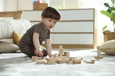 Photo of Cute little child playing with wooden building blocks at home. Space for text