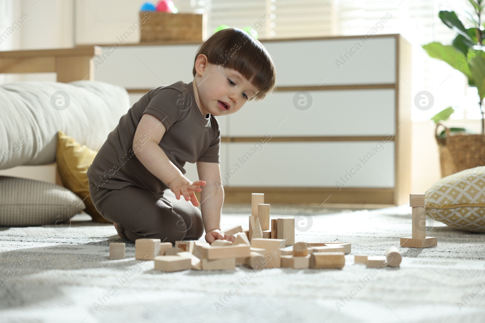 Photo of Cute little child playing with wooden building blocks at home. Space for text