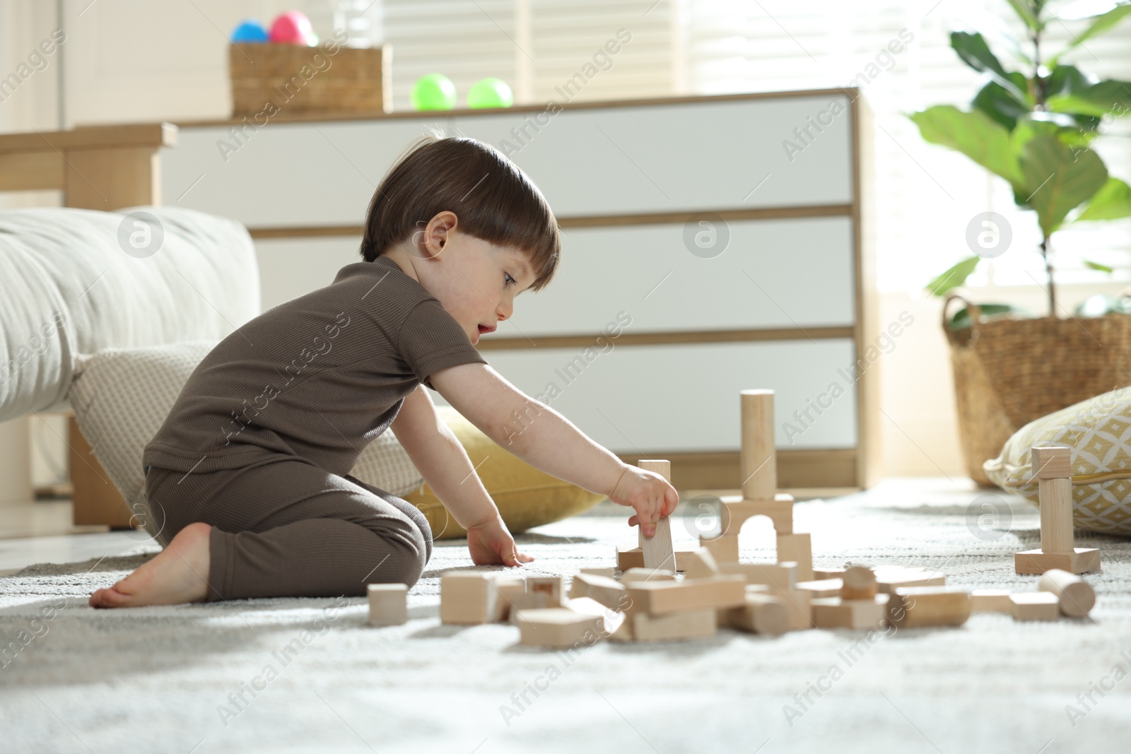Photo of Cute little child playing with wooden building blocks at home