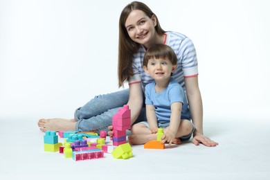 Photo of Mother and son playing with building bricks on white background