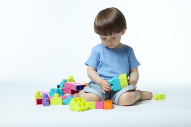 Photo of Cute little boy playing with building bricks on white background