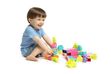 Photo of Cute little boy playing with building bricks on white background