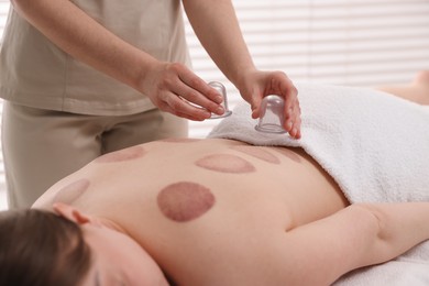Photo of Therapist giving cupping treatment to patient in spa salon, closeup