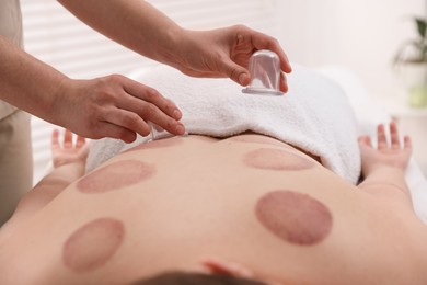 Photo of Therapist giving cupping treatment to patient in spa salon, closeup