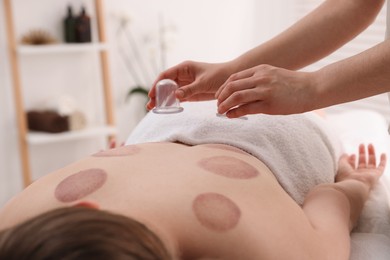 Photo of Therapist giving cupping treatment to patient in spa salon, closeup