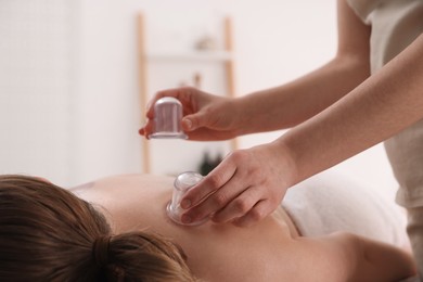 Photo of Therapist giving cupping treatment to patient in spa salon, closeup