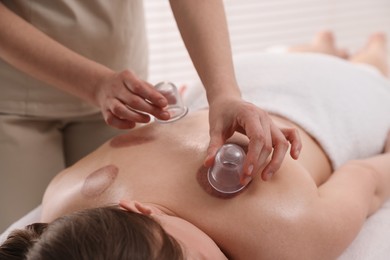 Photo of Therapist giving cupping treatment to patient in spa salon, closeup