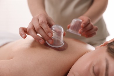 Photo of Therapist giving cupping treatment to patient in spa salon, closeup