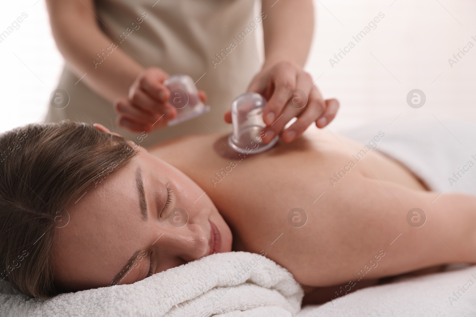 Photo of Therapist giving cupping treatment to patient in spa salon, closeup