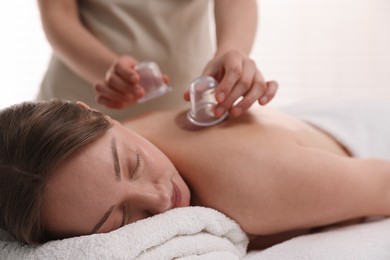 Photo of Therapist giving cupping treatment to patient in spa salon, closeup