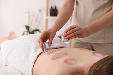Photo of Therapist giving cupping treatment to patient in spa salon, closeup