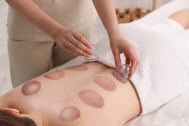 Photo of Therapist giving cupping treatment to patient in spa salon, closeup