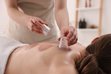 Photo of Therapist giving cupping treatment to patient in spa salon, closeup