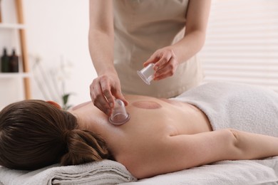 Photo of Therapist giving cupping treatment to patient in spa salon, closeup