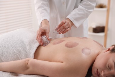 Photo of Therapist giving cupping treatment to patient in spa salon, closeup