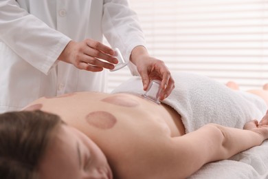 Photo of Therapist giving cupping treatment to patient in spa salon, closeup