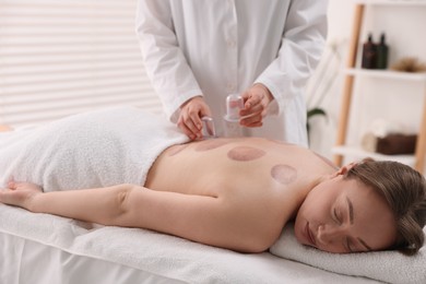 Photo of Therapist giving cupping treatment to patient in spa salon, closeup