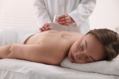 Photo of Therapist giving cupping treatment to patient in spa salon, closeup