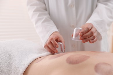 Photo of Therapist giving cupping treatment to patient in spa salon, closeup