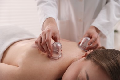 Photo of Therapist giving cupping treatment to patient in spa salon, closeup