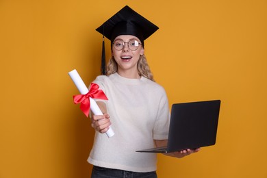 Photo of Happy student with diploma and laptop after graduation on orange background