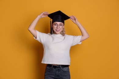 Photo of Happy student after graduation on orange background