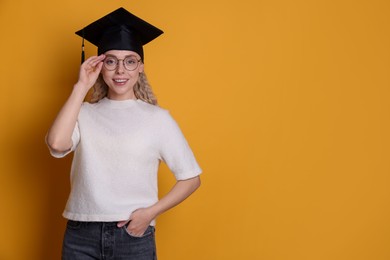Photo of Happy student after graduation on orange background. Space for text