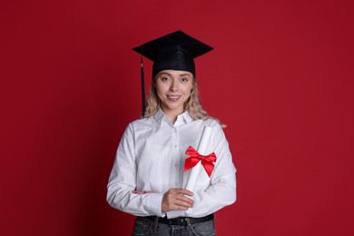 Photo of Happy student with diploma after graduation on red background