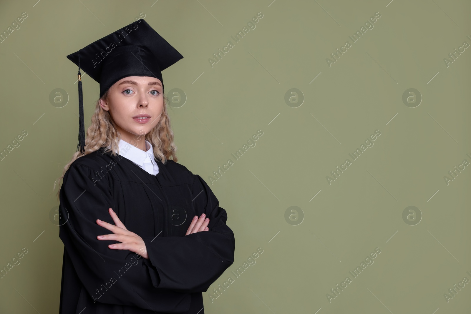 Photo of Student with crossed arms after graduation on green background. Space for text