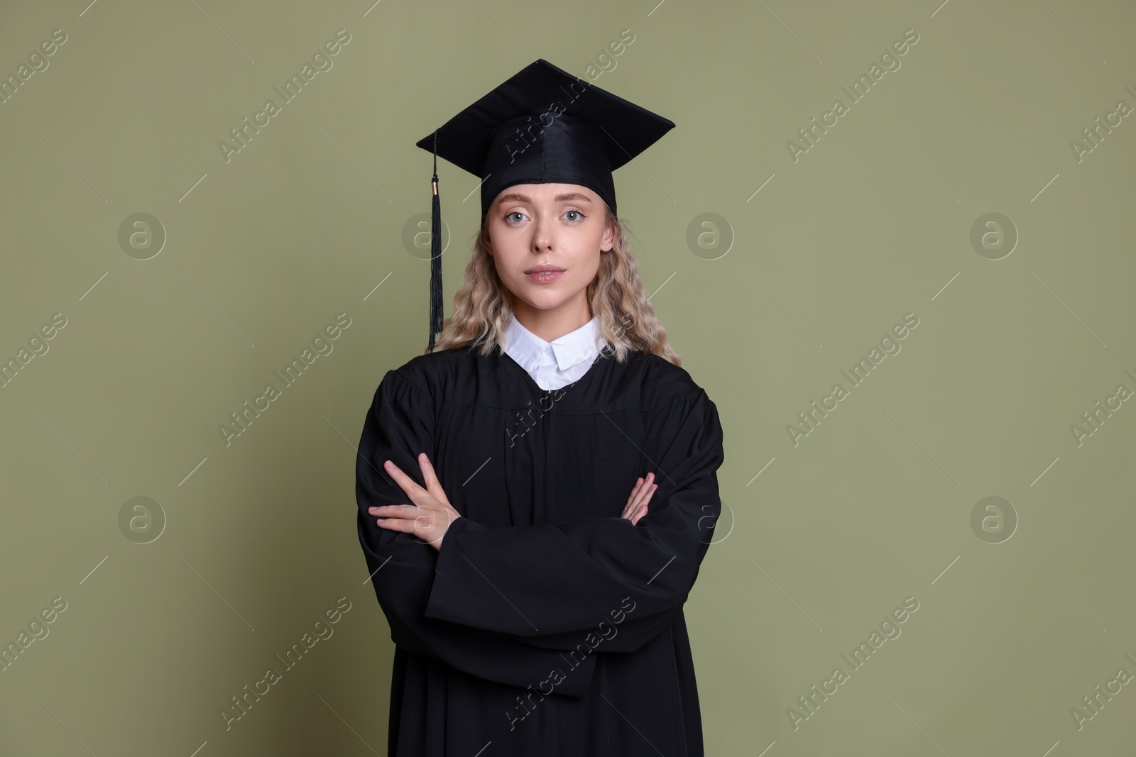 Photo of Student with crossed arms after graduation on green background