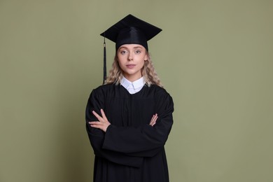 Photo of Student with crossed arms after graduation on green background