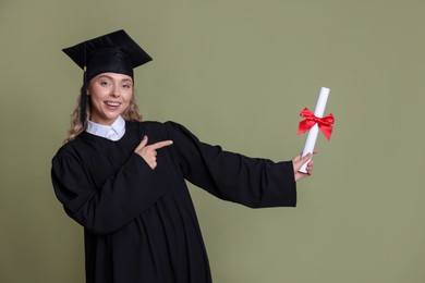 Photo of Happy student pointing at diploma after graduation on green background