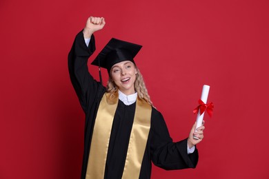 Photo of Happy student with diploma after graduation on red background
