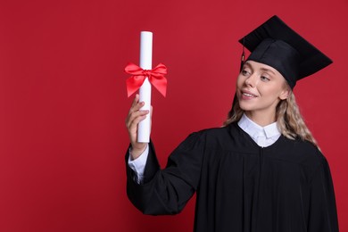 Photo of Happy student with diploma after graduation on red background. Space for text