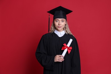 Photo of Student with diploma after graduation on red background