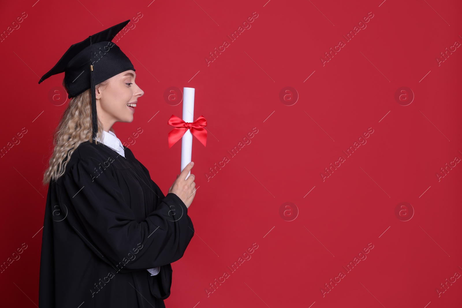 Photo of Happy student with diploma after graduation on red background. Space for text