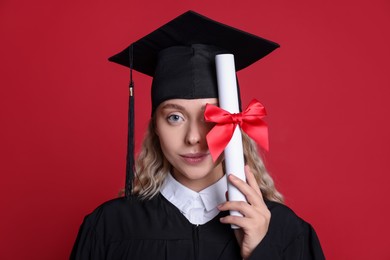Photo of Beautiful student with diploma after graduation on red background
