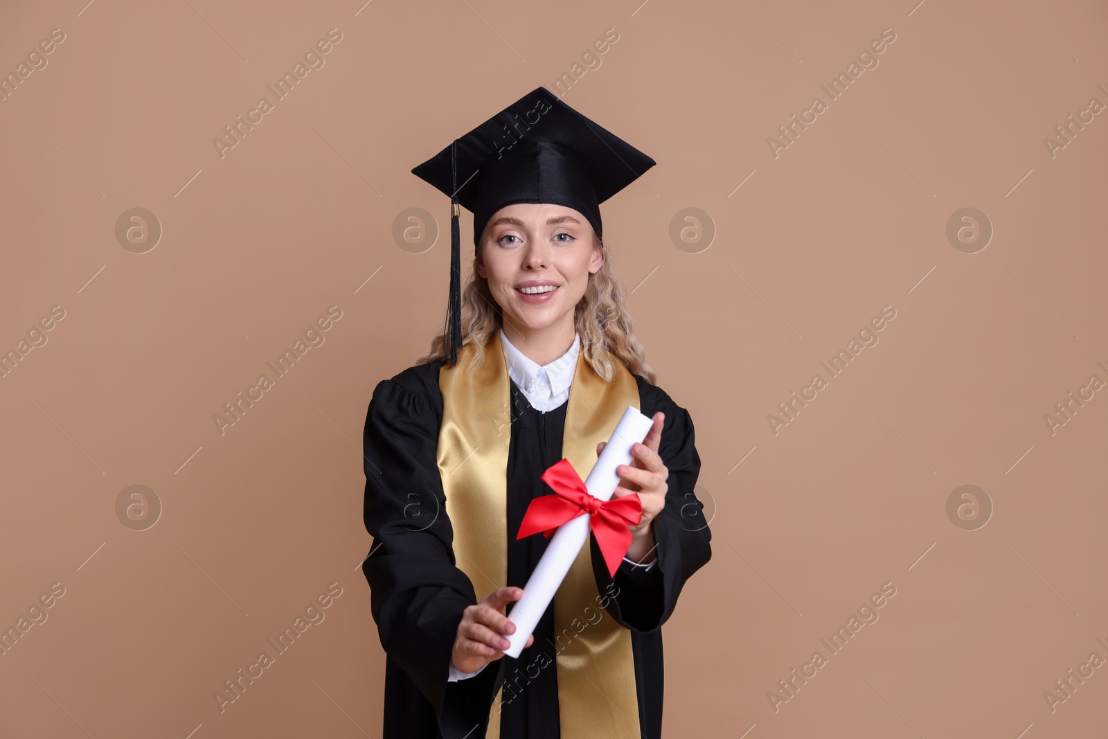 Happy student with diploma after graduation on beige background Photo of Happy student with diploma after graduation on beige background