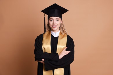 Photo of Happy student with crossed arms after graduation on beige background