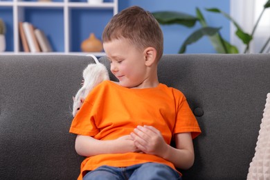 Photo of Little boy with his pet rat on sofa at home