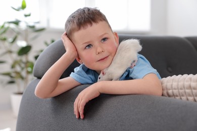Photo of Little boy with his pet rat on sofa at home