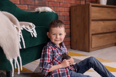 Photo of Little boy with his pet rat on floor at home